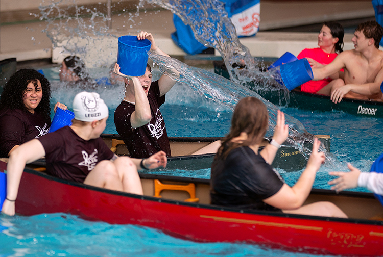 Students bailing out their canoes with buckets with Canoe Swamp  Event
